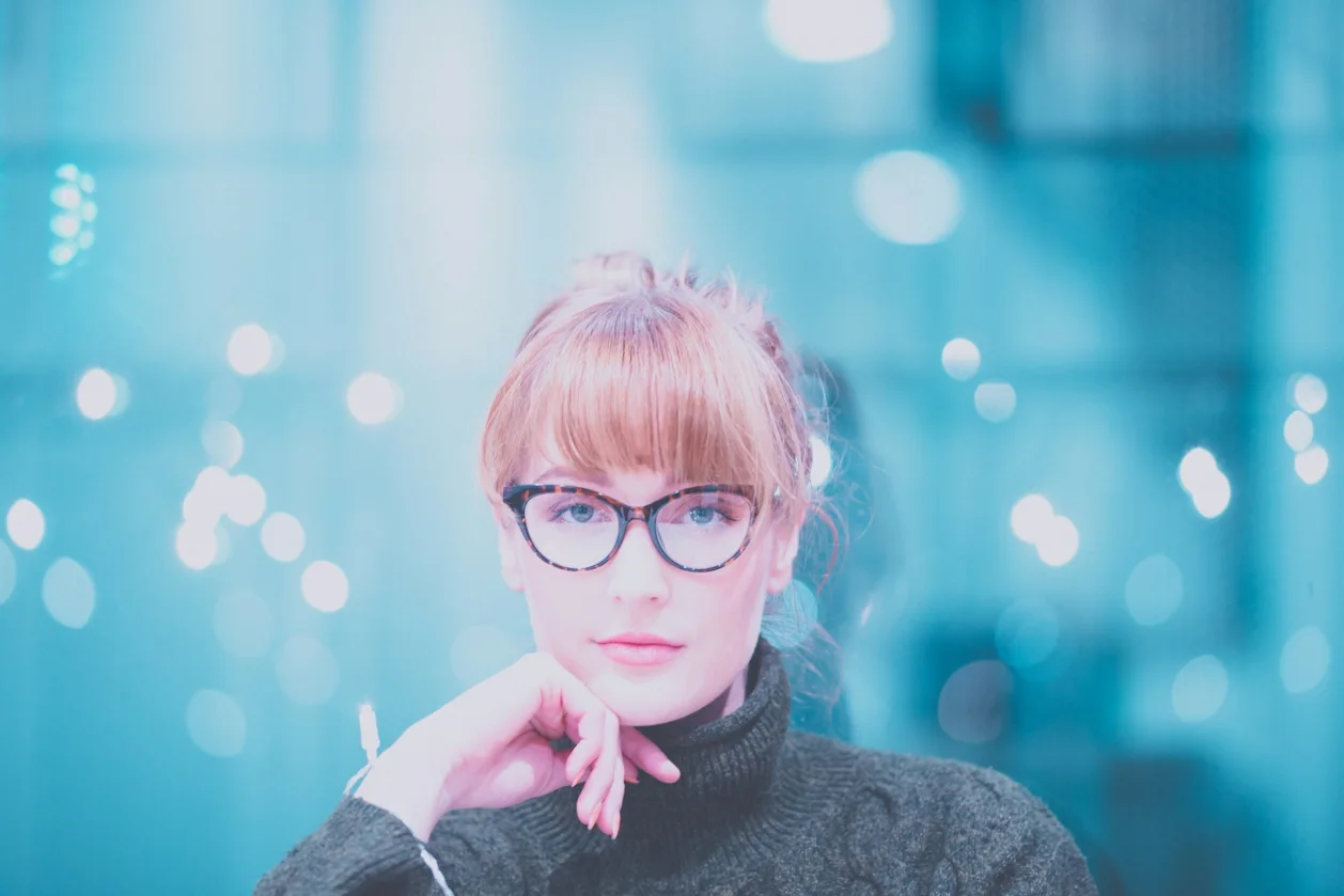 woman wearing glasses with fairy lights in background